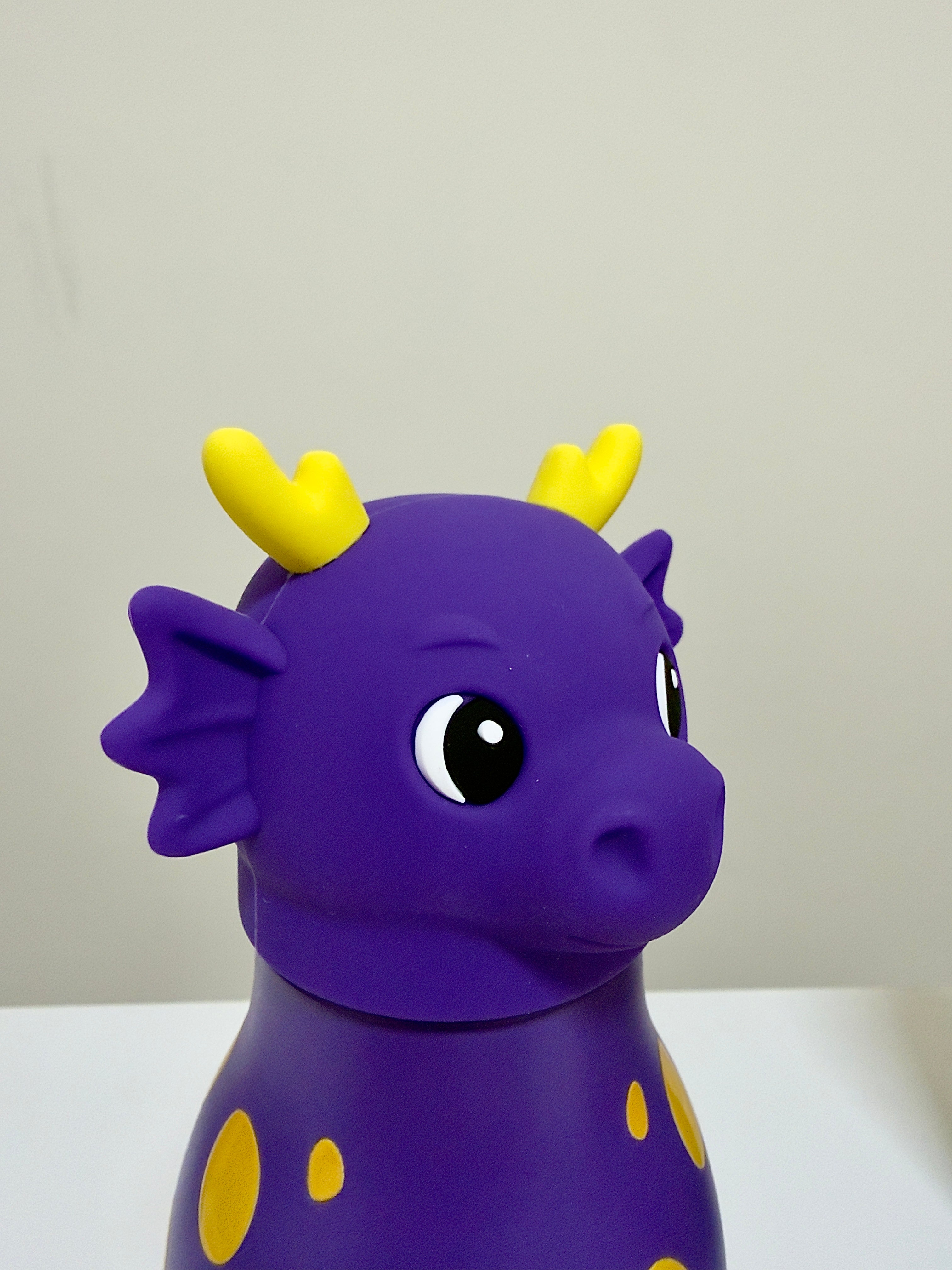 A purple dragon-shaped container or toy with yellow horns and yellow spots, photographed against a plain light background.